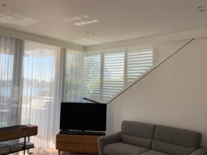 Custom shaped white PVC plantation shutter fitted to a raked living room window in Bulimba