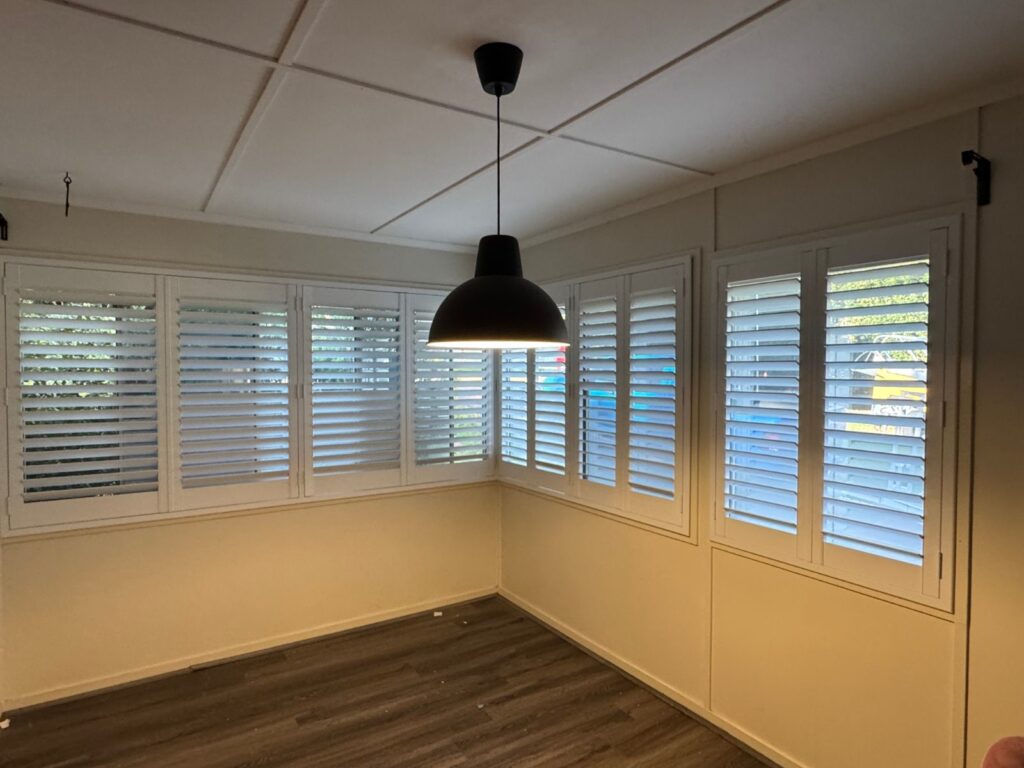 White PVC plantation shutters fitted to a living room window in Kallangur