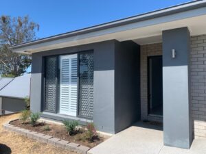 White PVC plantation shutters fitted to a street-facing window on a Burpengary home